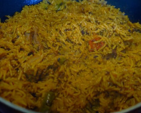 A vibrant plate of Kerala-style mutton pulao garnished with spices and herbs, served with raita.