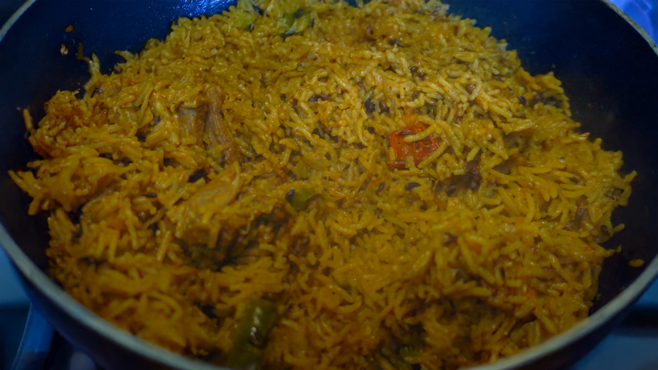 A vibrant plate of Kerala-style mutton pulao garnished with spices and herbs, served with raita.