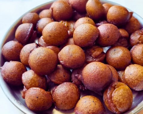 A plate of golden-brown Kerala-style unniyappam, garnished with black sesame seeds, served fresh and hot.