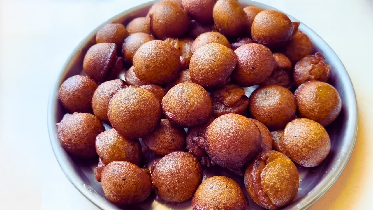 A plate of golden-brown Kerala-style unniyappam, garnished with black sesame seeds, served fresh and hot.