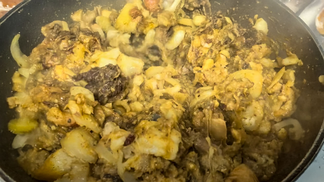 A vibrant dish of Chakka Kottittu Vechathu, a traditional Kannur delicacy, served in a clay pot with garnished curry leaves and tempered spices, showcasing a rich, textured mix of jackfruit and beef.