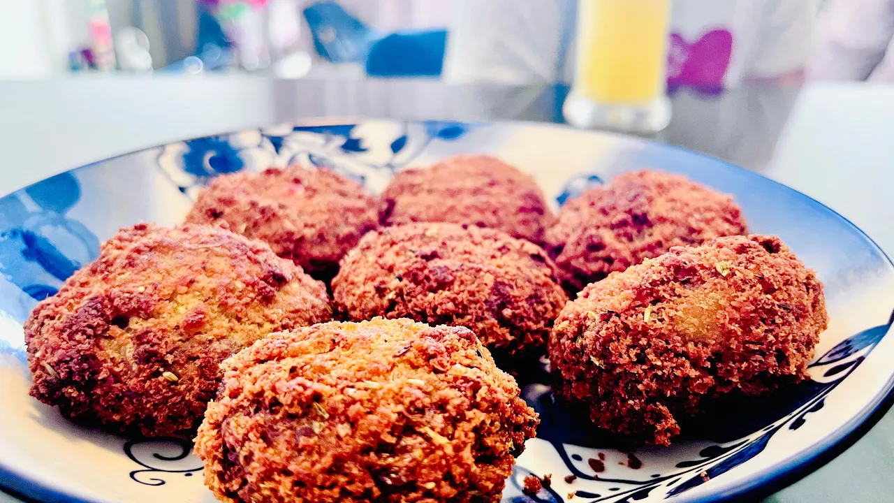 Homemade crispy beef cutlet served on a plate with a side of ketchup, garnished with fresh coriander leaves.